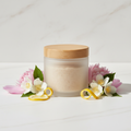 Sheer Petal Body Scrub in a rice husk jar with soft floral props