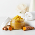 Turmeric Glow Body Scrub Travel Size with golden turmeric scrub and white towels