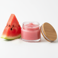 Pink Melon Lip Scrub in a 2oz glass jar with natural wooden lid open, fresh watermelon slice on bright white background