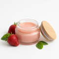 Strawberry Lip Butter Balm in a 2oz glass jar with natural wooden lid open, smooth glossy balm texture, fresh strawberries on white background