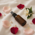 I Am Woman Room Mist - amber bottle on white linen with rose petals, jasmine and pearls