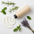 Rosemary Retreat Body Lotion bottle on its side with lotion and rosemary, peppermint, lavender props